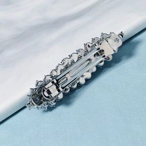 Detail of silver spring hair clip showing the back mechanism on marble surface