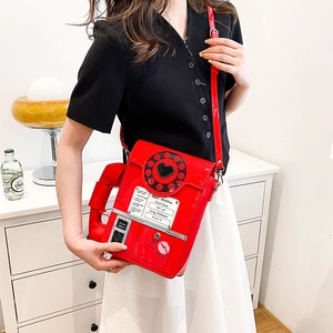 Detail of red vintage telephone shaped crossbody bag made of shiny patent leather material