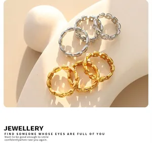 Polished gold and silver chain link rings displayed on a modern white stand