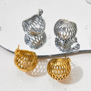 Hohlkugelförmige Gitterohrringe in Gold und Silber auf einer reflektierenden Wasserfläche