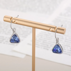 Close-up of blue triangle crystal earrings hanging on a metal jewelry display stand