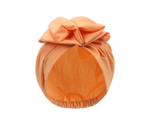 Detail of baby turban hat in light orange featuring a large bow and elastic fabric texture