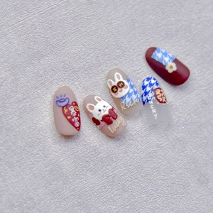 Close-up of 3D rabbit nail stickers with lucky charms and plaid patterns in festive style