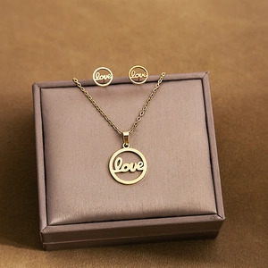 Macro shot of gold stainless steel necklace and earrings set with hollow love script