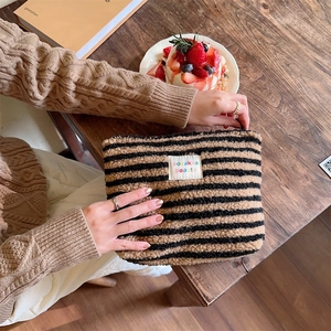 Detail of plush brown and black striped vanity bag featuring a colorful embroidered textile label
