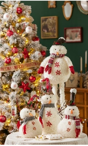 Dettagli di pupazzi di neve in peluche con sciarpe festive vicino a un albero