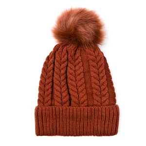 Détail de la maille torsadée et du grand pompon en fausse fourrure sur bonnet caramel