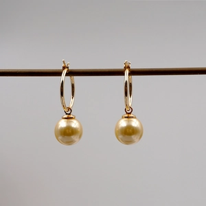 Vista dettagliata di eleganti orecchini con grandi perle dorate e ganci a cerchio d'oro