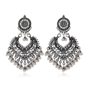 Detail of silver hollowed heart earrings with bells and intricate bohemian patterns
