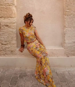 Detail of yellow floral lace two-piece set featuring mesh crop top and maxi skirt