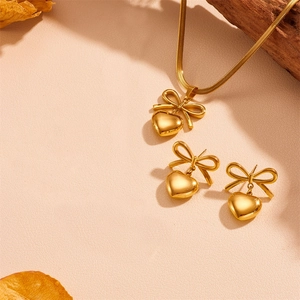 Golden bow and heart jewelry set with necklace and earrings on a warm autumn background