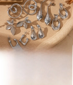 Macro shot of silver titanium steel earrings set with leaf and mobius geometric designs