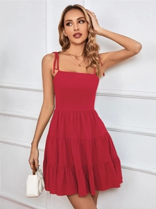 Detail of red tiered mini dress featuring adjustable bow tie straps and layered ruffled hem