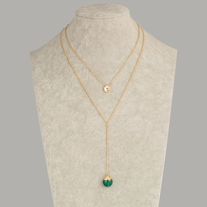 Collier double rang doré avec perle en pierre verte et pendentif disque sur un modèle
