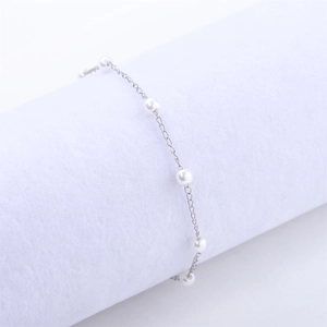 Gros plan d'un bracelet élégant en perles de 4mm sur un support à bijoux blanc minimaliste