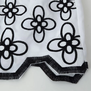 White long-sleeved resort shirt with black floral embroidery and zigzag trim