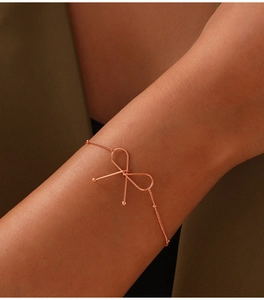 Close-up of minimalist rose gold bow bracelet on wrist featuring polished titanium steel