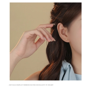 Close-up of golden mini bow stud earring worn on ear, crafted in S925 sterling silver