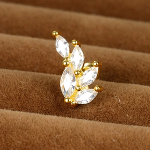 Detailed close-up of a golden leaf earring with zircon stones on brown velvet