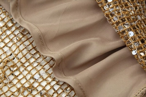 Vue macro de paillettes dorées sur tulle avec doublure soyeuse beige pour robe chic