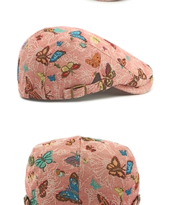 Detail view of red jacquard newsboy cap with butterfly patterns and adjustable metal buckle