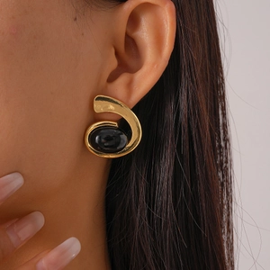 Gros plan sur des boucles d'oreilles spirales dorées avec une pierre noire ovale rétro