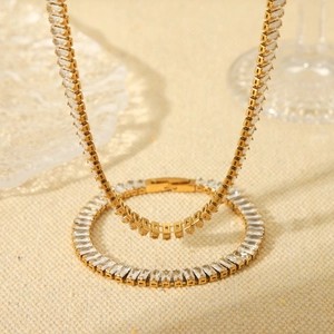 Golden tennis necklace and bracelet set with rectangular cubic zirconia on beige fabric