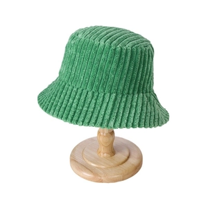 Green corduroy bucket hat for women on wooden stand, warm minimalist autumn winter design