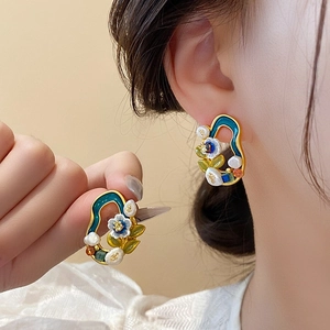 Close-up of Monet-style floral pearl earring featuring blue enamel and gold metal frame