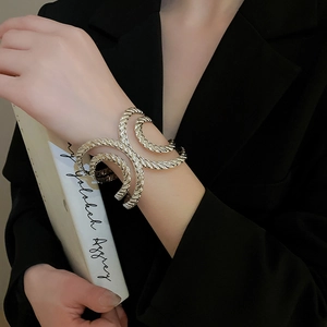 Close-up of irregular textured silver twisted bangle worn on wrist over black suit jacket