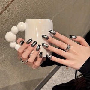 Gothic black and metallic silver coffin shaped press-on nails shown on a creative mug
