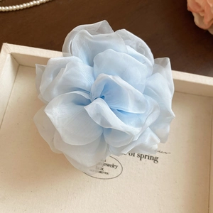 Nahaufnahme eines hellblauen Chiffon-Blütenhaarschmucks in einer beigen Schmuckbox