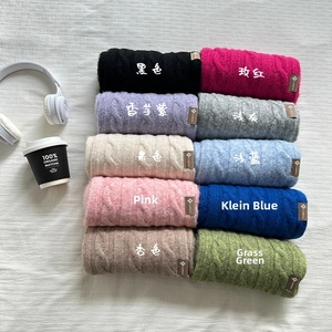 Close-up showing various colors of cable knit wool scarves in a soft textured display