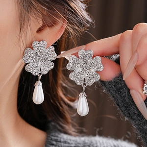 Detail of silver clover earrings with sparkling rhinestones and elegant pearl pendants