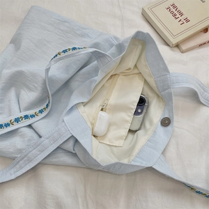 Detail view of cotton-linen tote interior with magnetic buckle and storage for gadgets