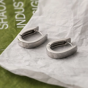 Minimalist silver-plated copper U-shape earrings on white textured paper backdrop