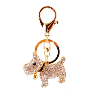 Sparkling gold puppy keychain with clear crystals and golden bell on white background