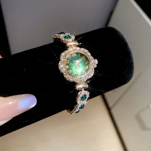 Detail of green sunray dial watch with rhinestone-encrusted gold bracelet on a stand