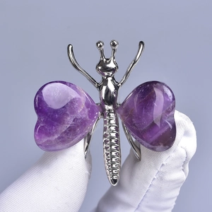 Silver butterfly ornament with heart-shaped purple crystals held in gloved hands