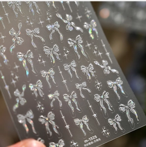 Close-up view of holographic bow nail art stickers showing shimmering shell luster effect.