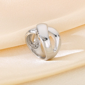 Detailed view of irregular cross hollow stainless steel ring on satin fabric