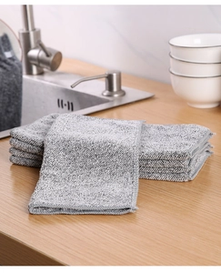 Macro shot of thick grey bamboo fiber cleaning cloths stacked on a wooden kitchen countertop
