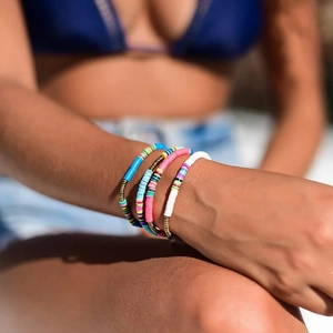 Close-up of four colorful beaded friendship bracelets on a model's wrist for summer style