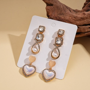Detail of vintage gold earrings with pearls and rhinestone heart studs on display