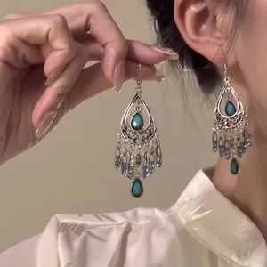Detailed close-up of exotic silver tassels with blue teardrop beads and teal gemstones