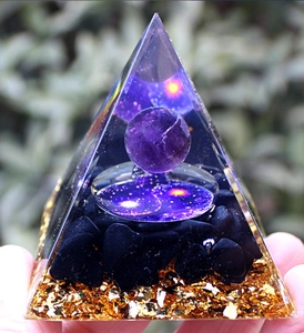Detailed macro view of Orgone pyramid with amethyst sphere, obsidian, and gold flakes
