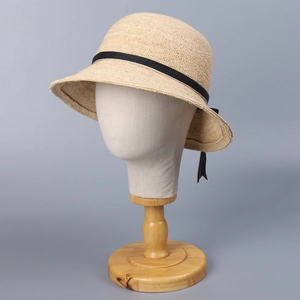Detail of raffia straw hat with black satin ribbon bow on a professional mannequin