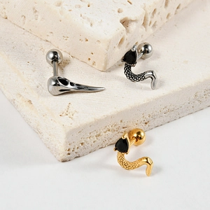 Detailed shot of skull and snake stud earrings with black zircon on stone background