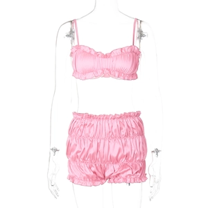 Detailed view of pink satin two-piece sleepwear set with ruffled camisole and matching shorts