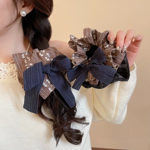Details von Vintage-Haargummis mit Blumenmuster und marineblauen Schleifen im Zopf